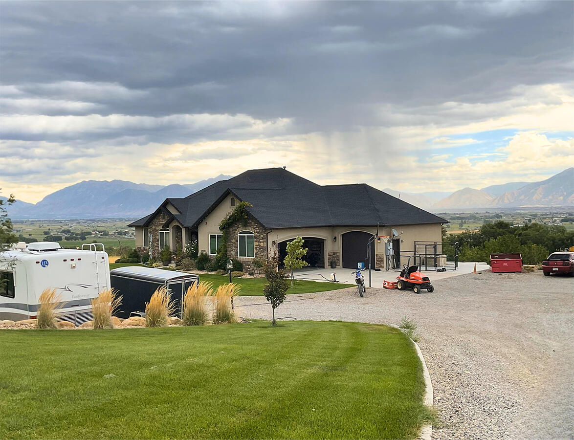 Brown house with lawn, with mountains and rain clouds in background